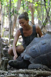 Woman looking at tortoise in forest