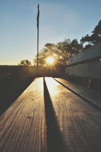 Close-up of wooden bench against sky during sunset