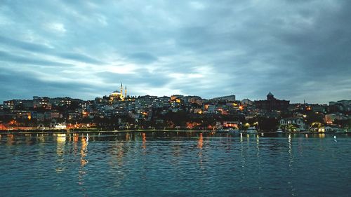 Buildings by river against sky at waterfront