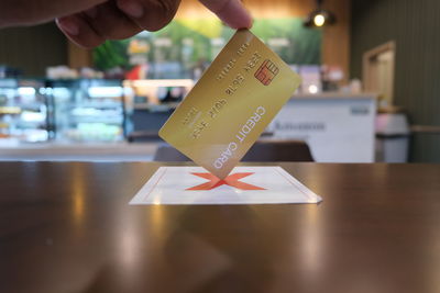 Close-up of hand holding paper with text on table