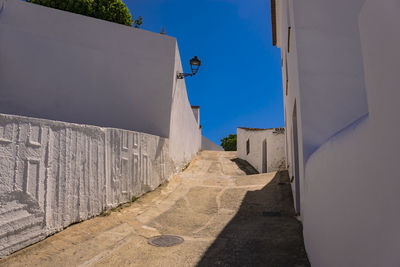 Street amidst buildings against blue sky