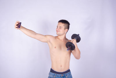 Full length of shirtless man standing against white background