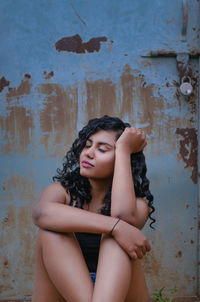 Young woman sitting against wall