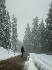 Rear view of man walking on snow covered landscape