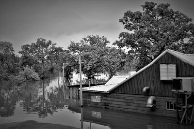 House by lake and trees against sky