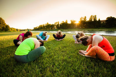 Group of people relaxing on grass at sunset