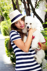 Portrait of young woman with dog against plants