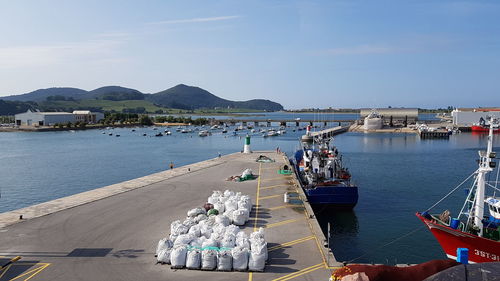 Boats moored at harbor by sea against sky