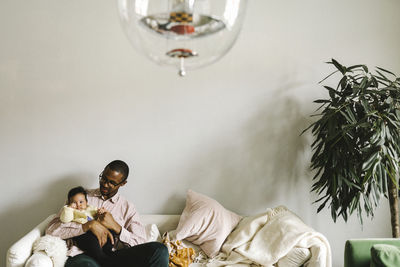 Father with baby daughter sitting on sofa