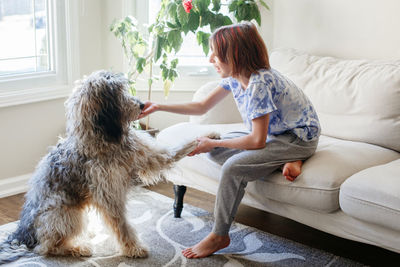 Side view of girl playing with dog at home