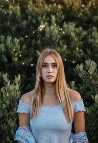 Portrait of beautiful young woman standing against tree