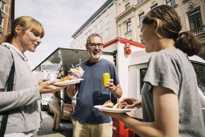 People eating snacks while standing against truck at city