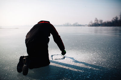 Man cutting hole in ice