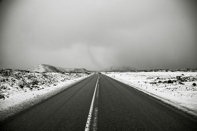 Empty road against sky during winter