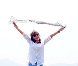 Portrait of smiling young woman standing against clear sky