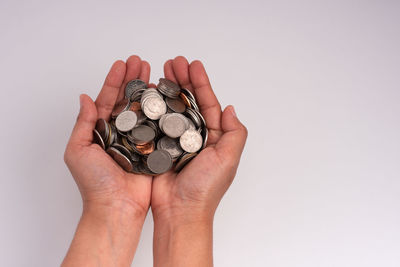 Close-up of hand holding ring over white background