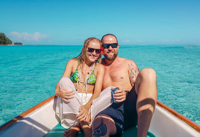 Portrait of man and woman in boat on sea against sky