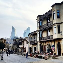 People walking on street in city against sky