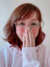 Portrait of beautiful woman covering mouth against white background