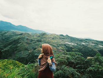 Woman wearing hijab while standing on field against sky