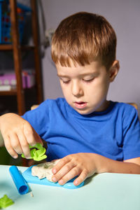 Boy playing with clay on table