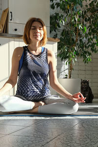 Portrait of young woman sitting in lotus yoga position at home. mental health 