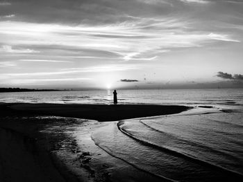 Silhouette of woman standing at shore of beach 