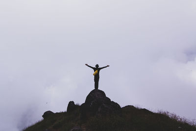 Man standing on rock against sky