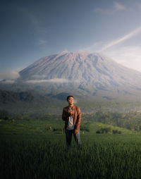 Young man smoking cigarette while standing against mountain