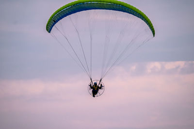 Man paragliding against sky during sunset