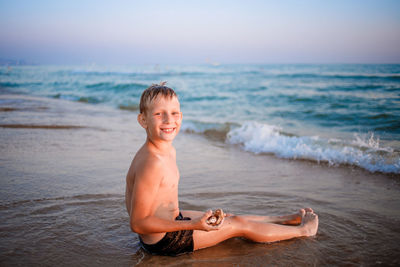 Portrait of happy boy at beach against sky