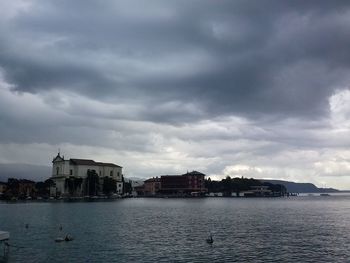 View of city by sea against cloudy sky