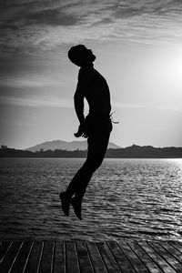 Silhouette man on lake against sky