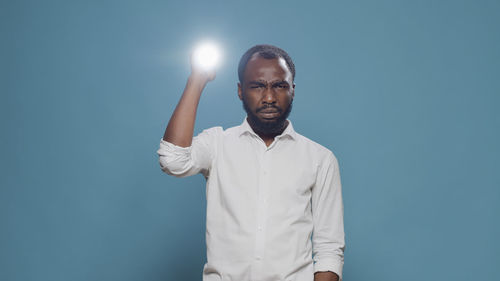 Portrait of young man standing against blue background