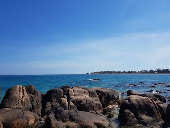 Rocks by sea against blue sky