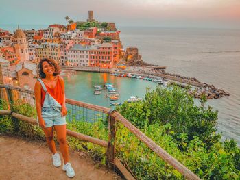 Portrait of man standing by railing against buildings in city