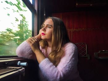 Portrait of beautiful young woman sitting in window
