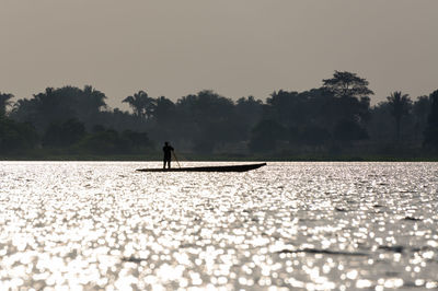 Silhouette fisherman sailing canoe in magdalena river