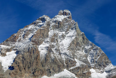 Low angle view of snowcapped mountain against blue sky