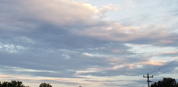 Low angle view of electricity pylon against sky during sunset