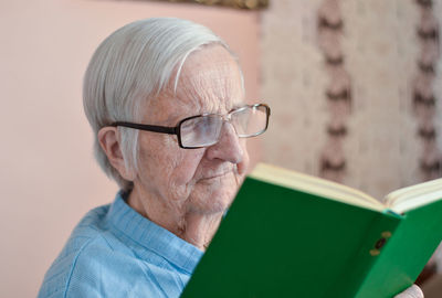 Old senior woman 90 years old holding open paper book in hands, reading best seller novel concept