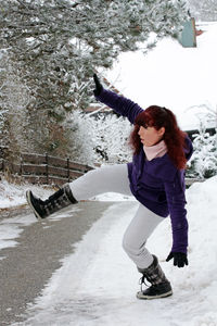 Full length of woman with arms raised in winter