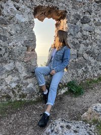 Full length of woman sitting on rock