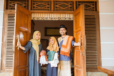 Portrait of happy family standing at door at home