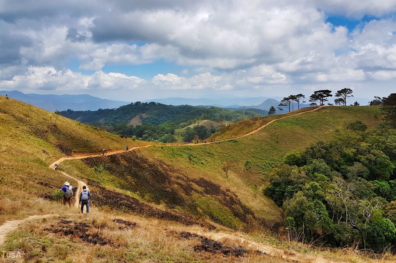 PEOPLE ON LANDSCAPE AGAINST MOUNTAIN RANGE