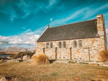 Old building by mountain against blue sky