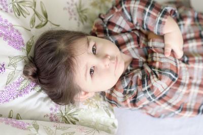 Close-up portrait of cute girl lying on bed at home