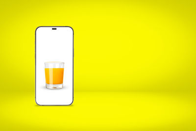 Low angle view of mobile phone on yellow wall