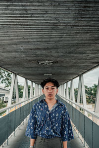 Portrait of young man standing against bridge