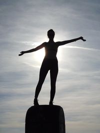 Man with arms outstretched standing against sky